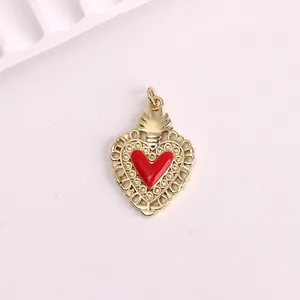 Close-up of a vintage gold heart pendant with red enamel center and filigree detail.