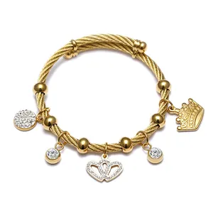 Vue détaillée d'un bracelet câble doré en acier avec breloques cœur et couronne