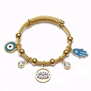 Détail d'un bracelet câble doré avec charms œil maléfique et main Hamsa