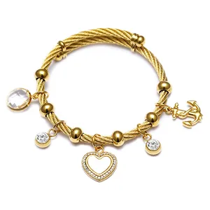 Vue détaillée d'un bracelet câble en acier inoxydable doré avec breloques cœur et ancre.