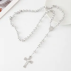 Detailed view of white beads and silver cross on stainless steel rosary necklace