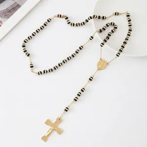 Detailed view of a stainless steel rosary necklace with black beads and a gold cross