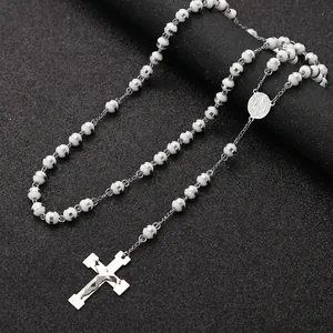 Detailed macro view of a stainless steel rosary necklace with white beads and crucifix