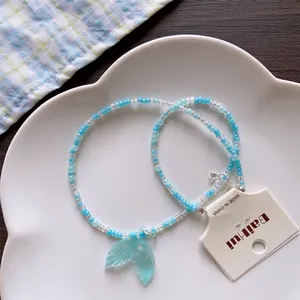 Detail view of summer blue beaded necklace featuring a translucent mermaid tail pendant