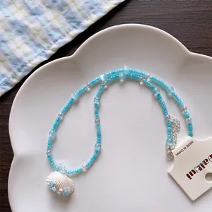 Detailed view of summer beach style shell beaded necklace displayed on a white plate