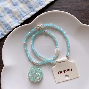 Close-up of summer beaded necklace featuring a shell pendant and a starfish charm.