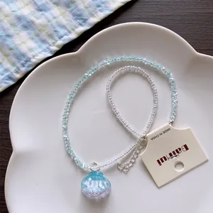 Detailed macro view of a blue shell pendant on a summer beaded necklace over a plate