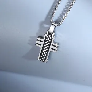 Close-up of a silver stainless steel cross pendant with checkered pattern