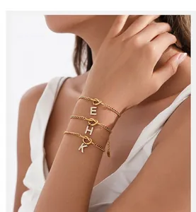 Detail of gold-plated stainless steel initial bracelet with sparkling diamond knot pendant