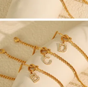 Detailed view of gold knotted bracelets with crystal-set B, C, and D letter charms