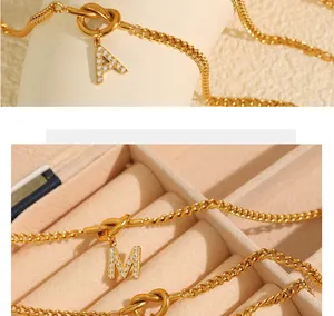 Detailed view of gold plated knot bracelet with crystal-encrusted letter pendants