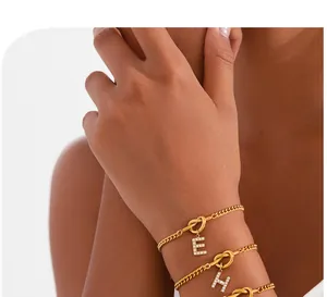 Close-up detail of 18k gold plated knot bracelets with sparkling rhinestone initial charms