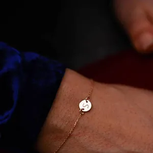 Delicate gold bracelet with engraved letter S round charm on wrist