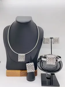 Detailed view of a silver stainless steel jewelry set with textured square woven patterns.