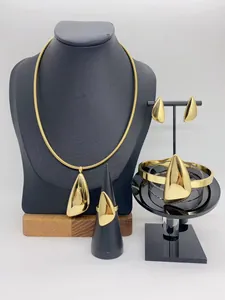 Detailed view of polished gold stainless steel jewelry set with geometric pendants.