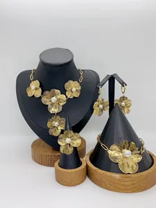 Detailed view of elegant gold flower jewelry set featuring pearls on display stands
