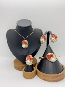 Full view of stainless steel jewelry set with red flowers and pearls on display stands.
