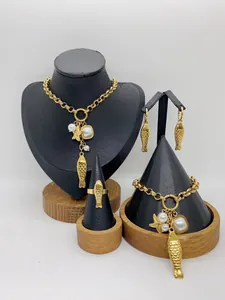 Close-up of gold stainless steel jewelry set featuring fish and pearl charms on displays
