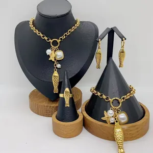 Luxury stainless steel jewelry set with fish charms and pearls on black display stands