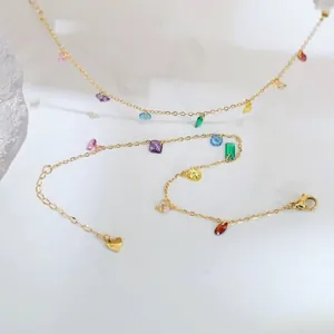 Detailed macro shot of a gold-plated chain bracelet with vibrant rainbow zircon charms