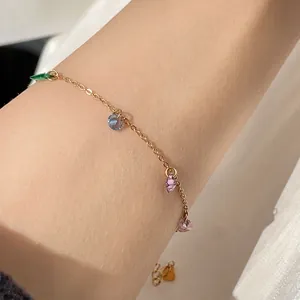 Detailed macro shot of gold chain bracelet with vibrant colorful zircon charms