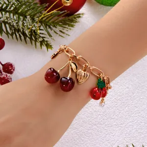 Detail view of sweet cherry charm bracelet with gold heart and resin fruit charms