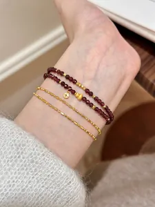 Detailed view of a double-strand natural garnet beaded bracelet with gold charms