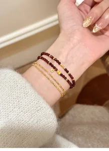 Elegant natural red garnet beaded bracelet and gold chain stacked on woman's wrist