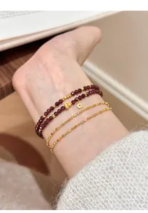 Close-up of natural garnet double-strand beaded bracelet layered with gold chains