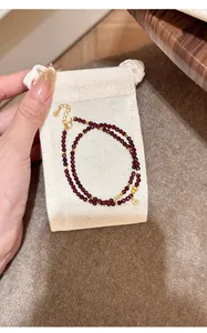 Close-up of double-strand natural garnet beaded bracelet with gold accents on a cream pouch