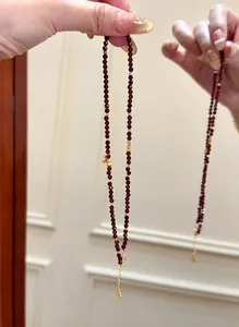 Detailed view of faceted natural garnet beaded bracelet with gold accents and gourd charm.