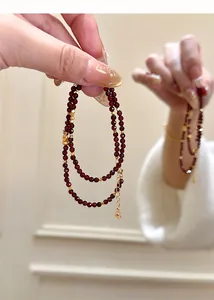 Detailed close-up view of a natural garnet double-strand beaded bracelet held by a hand