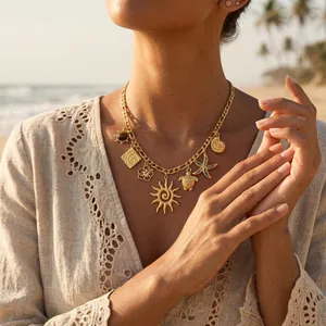 Collier bohème en acier inoxydable doré avec pendentifs soleil et mer sur une plage.
