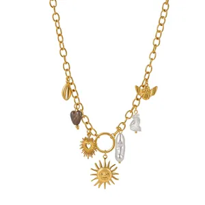 Collier en acier inoxydable doré avec breloques soleil, cœur et perle sur fond blanc