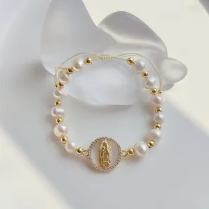 Close-up detail of natural pearl beaded bracelet with a golden Virgin Mary charm