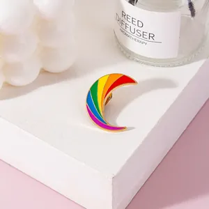 Close-up of a vibrant rainbow moon-shaped metal enamel brooch with a glossy finish