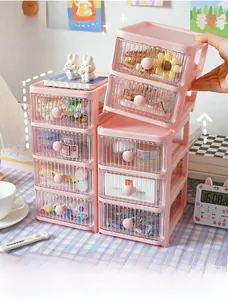 Hand stacking pink desktop drawer organizers for stationery and makeup storage.