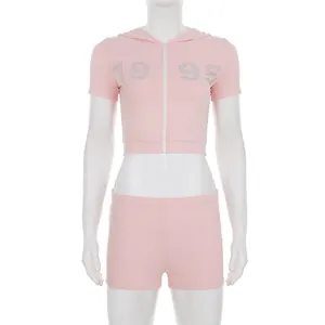 Detail of pink two-piece tracksuit with rhinestone 1995 logo and hooded zip top.