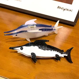 Close-up of artistic swordfish-shaped acetate hair claw clips in blue and black colors.