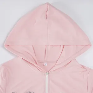 Close-up detail of a pink hooded zip-up top with rhinestone accents and soft fabric