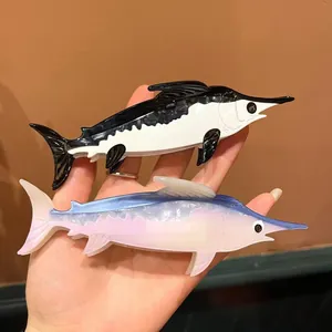 Detail view of swordfish-shaped acetate hair claws in black and pearlescent blue