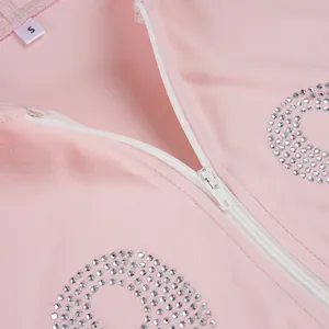 Close-up detail showing the white zipper and rhinestone decor on pink hooded top