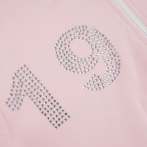Detailed view of pink tracksuit featuring shimmering rhinestone number 19 design