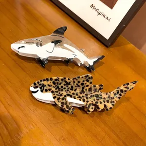 Detailed view of two shark-shaped acetate hair claws in white and leopard print.