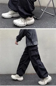 Detail view of black vintage cargo pants with drawstring hem and chunky sneakers