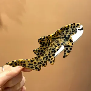 Detailed close-up of a leopard shark shaped acetate hair claw clip with black spots