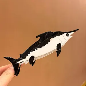 Detailed view of a swordfish-shaped acetate hair claw clip in sleek black and white finish.