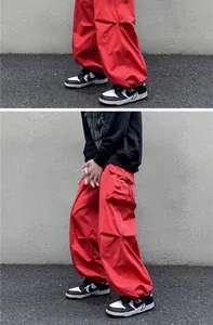 Close-up detail of baggy red cargo pants with drawstring hems and utility pockets.
