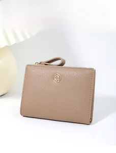 Macro detail of a taupe pebbled leather bifold wallet featuring a gold-toned circular logo