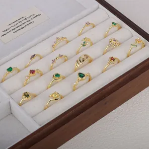 Collection of vintage gold-plated rings with colorful gemstones in wooden display box